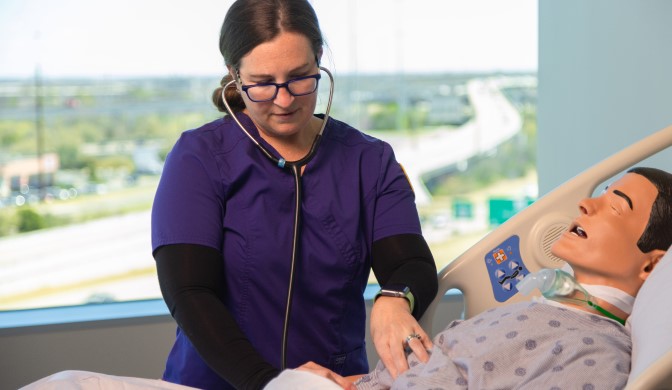 A Concordia Nursing student on campus working in a sim lab