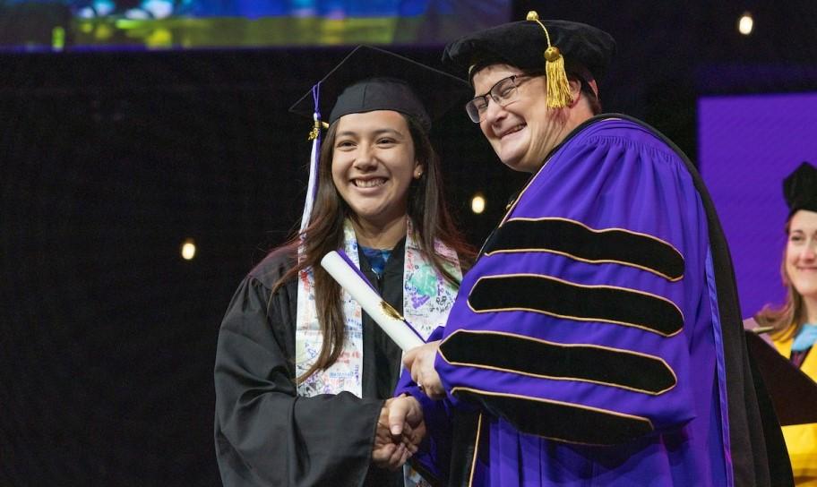 Dr. Kirk handing out degrees and shaking the hands of graduates.