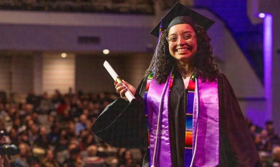 A student walking to get her degree at commencement.