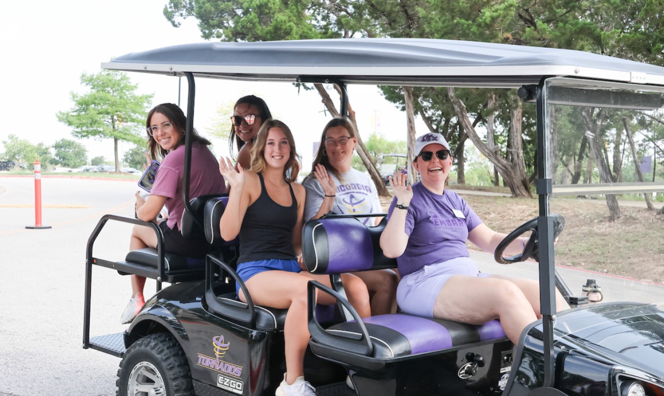 Students on a golf cart moving on campus