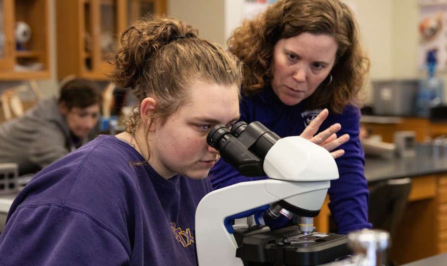 A professor assiting a student in a biology lab