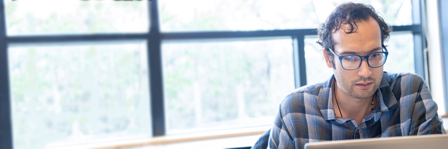 Adult man with glasses looking at laptop computer