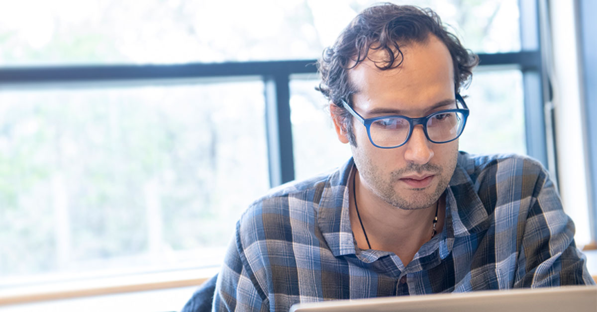 Adult man with glasses looking at laptop computer