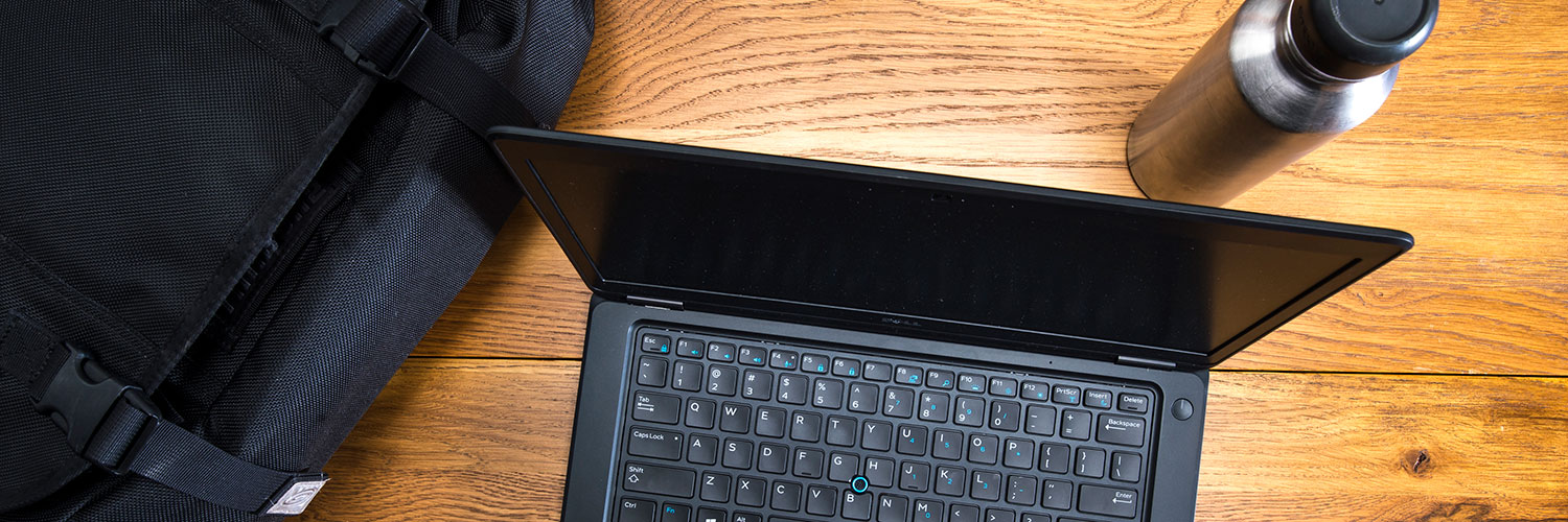 laptop on desk with backpack and stainless steel water bottle