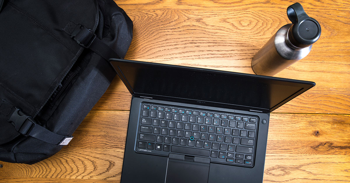 laptop on desk with backpack and stainless steel water bottle