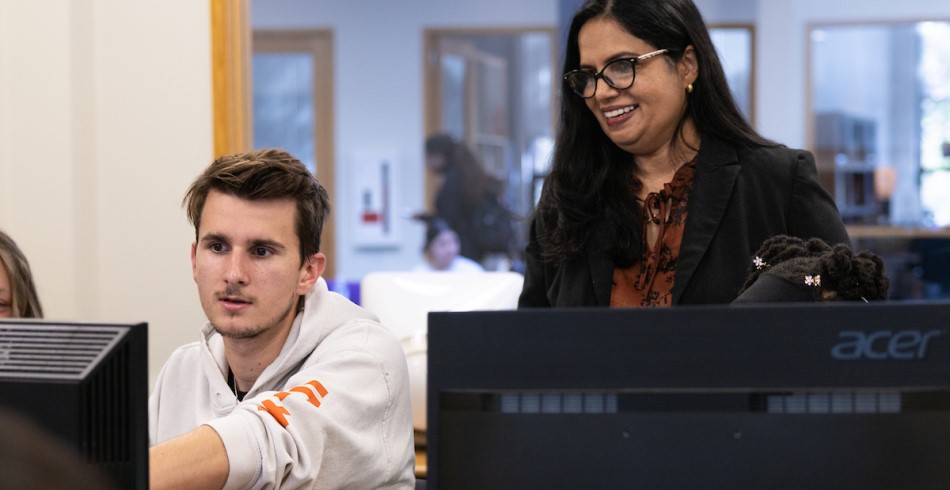 Computer science professor helping a student in a computer lab