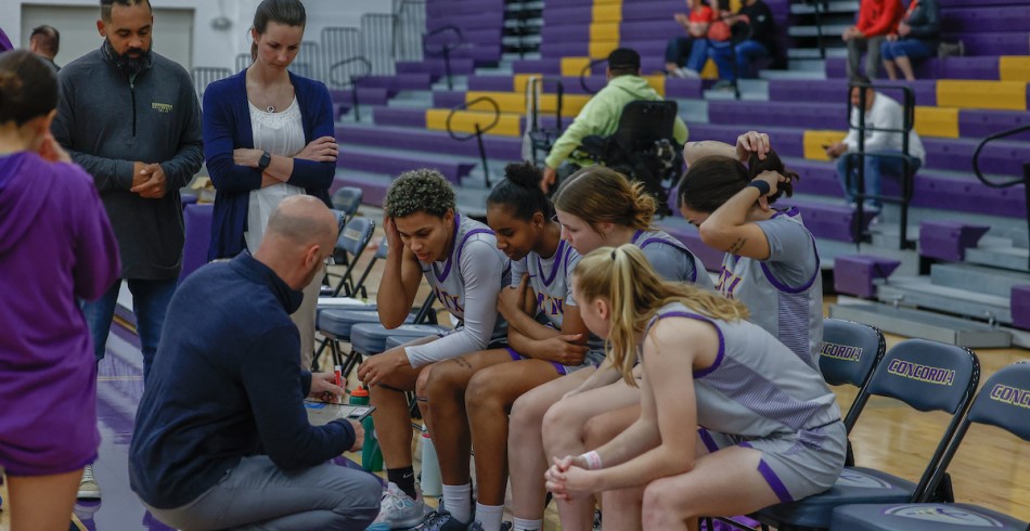 Concordia Texas coach leading his team during a basketball game