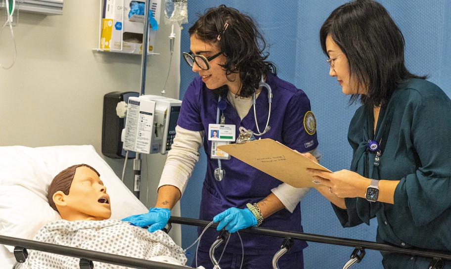 A nursing student working in the simulation lab with a professor