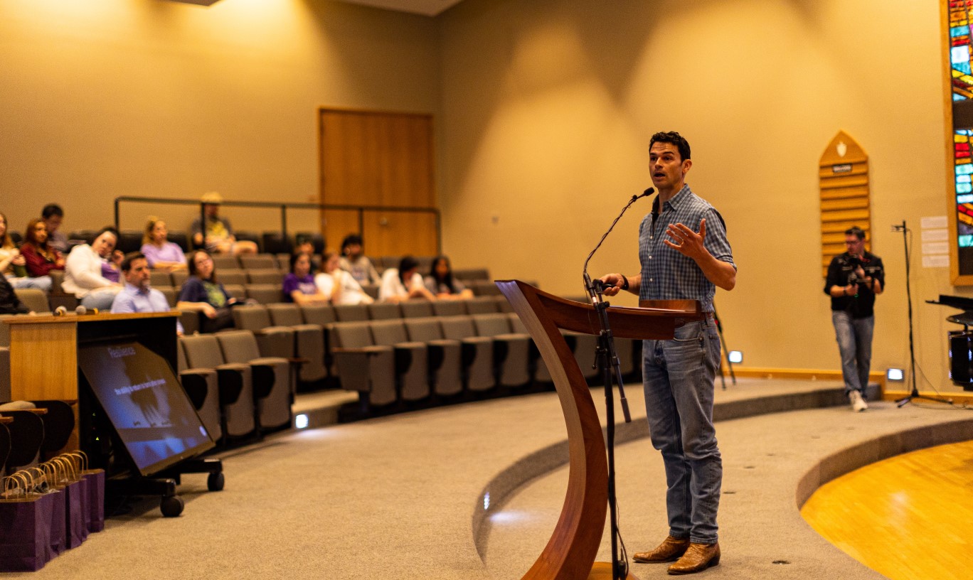 A student pitching a new product to a panel of judges and an audience.