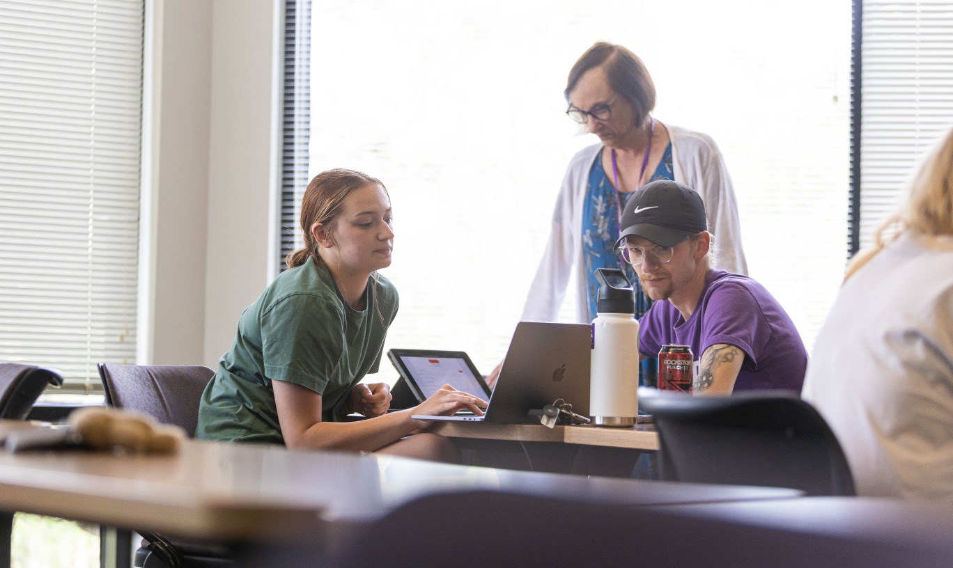 A pair of students getting advice from a professor